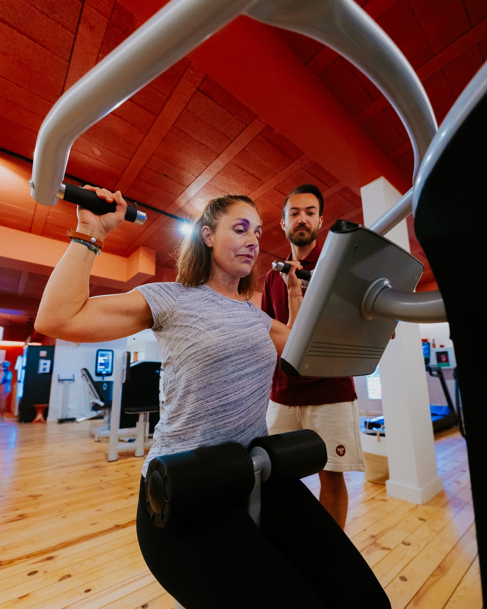 Femme en séance sur machine EGYM, coach en accompagnement