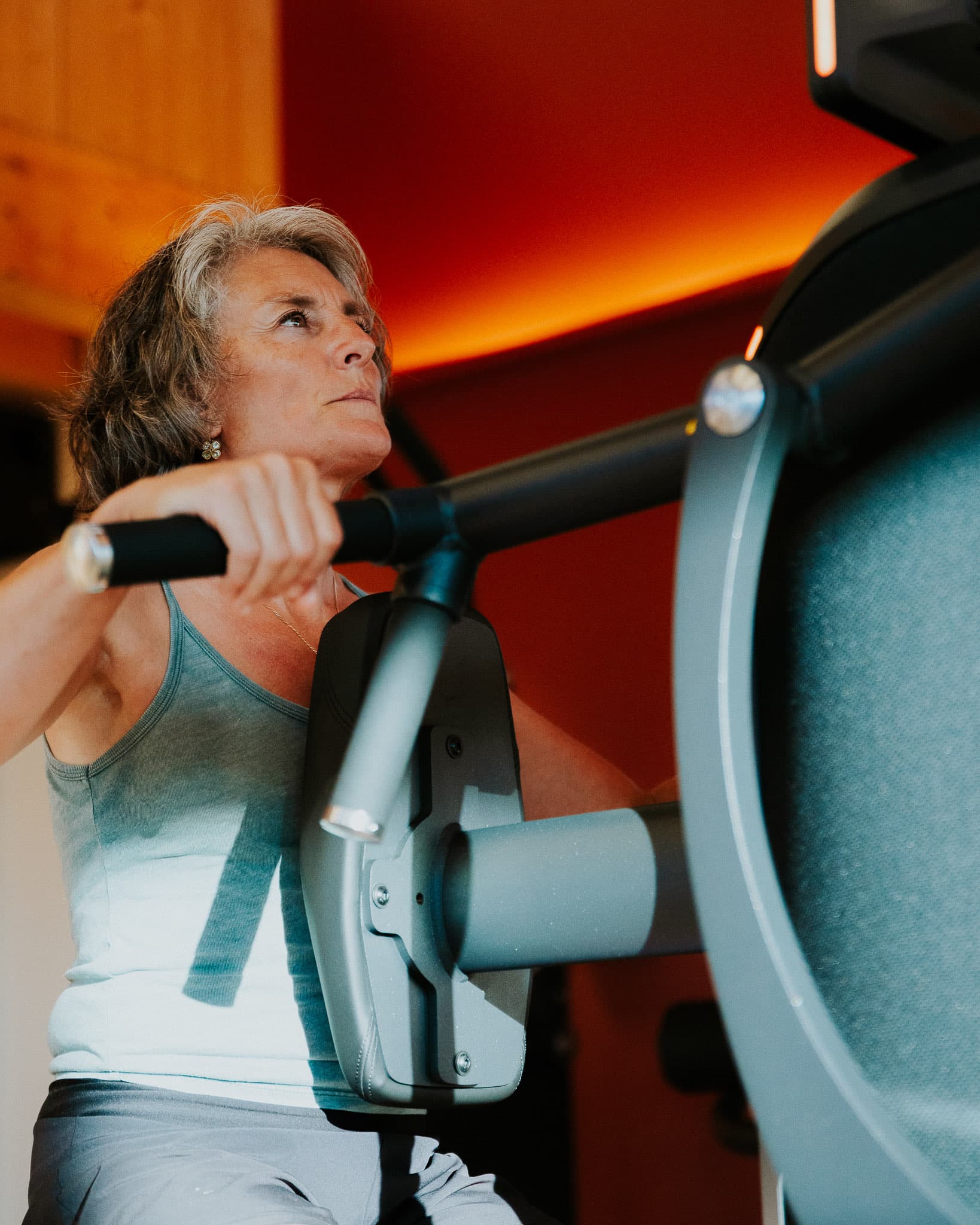 Membre senior en séance sur une machine EGYM, devant un mur terracotta