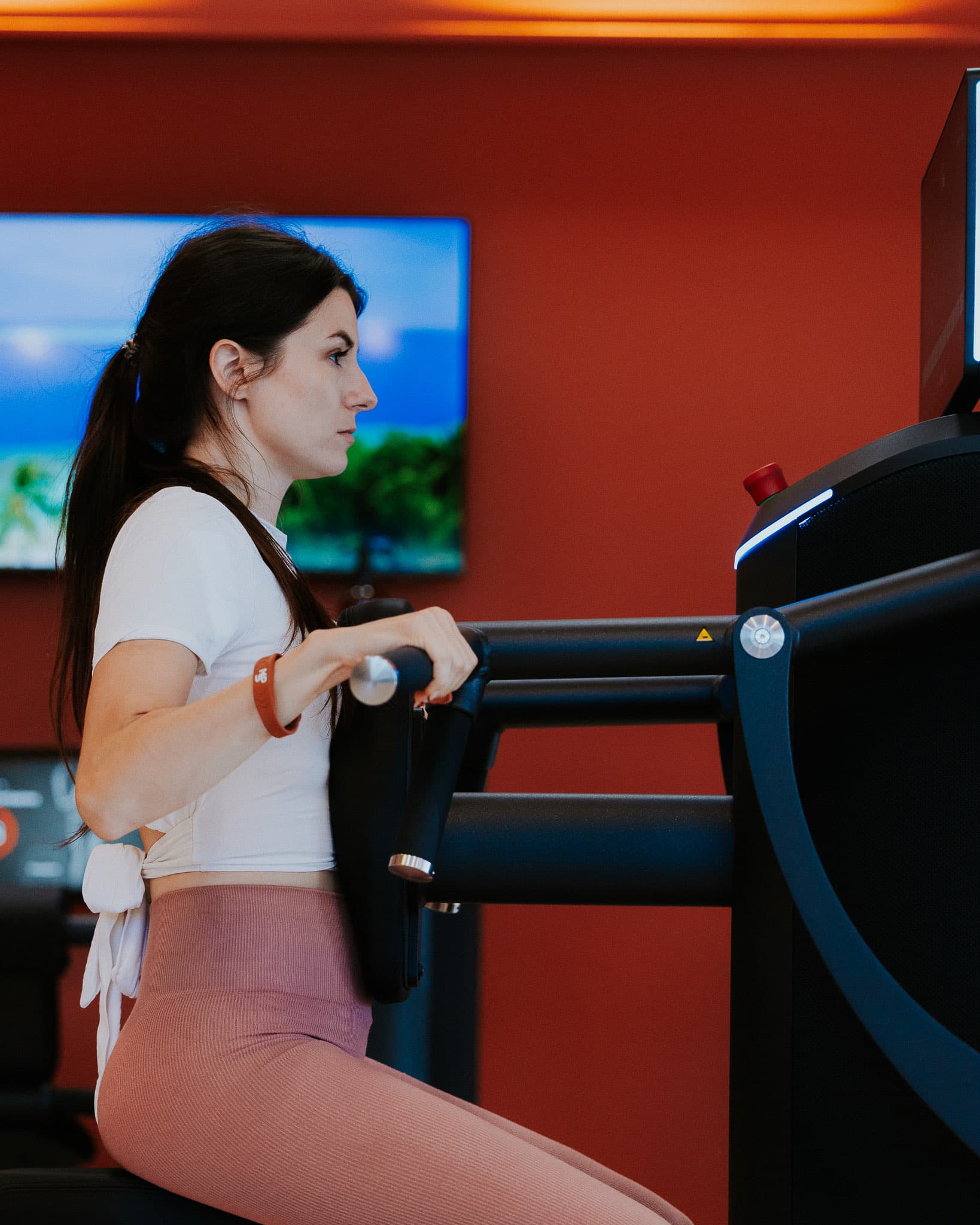 Membre en séance sur une machine EGYM, bracelet terracotta au poignet